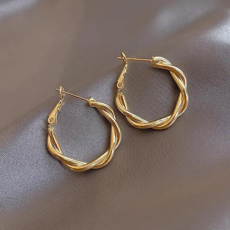 Elegant gold twisted hoop earrings for women, featuring a chic and modern design that adds sophistication to any outfit.
