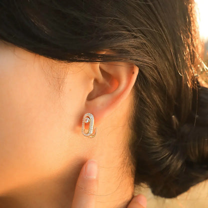 Geometric paper clip earrings on the left ear.