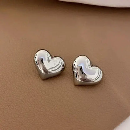 Charming silvery heart stud earrings for women, featuring a smooth, polished design perfect for adding a touch of love to any outfit.